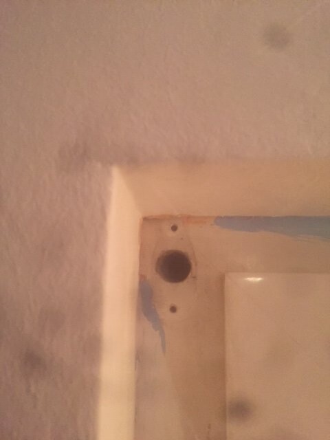 Close-up of a wall frame with perforation and visible blue tape