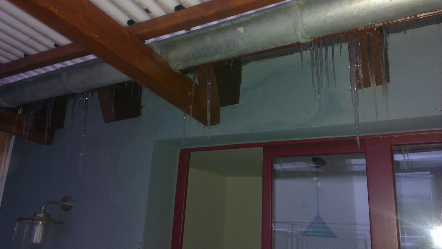 Interior with wooden beams, icicles on pipes, red door with glass window.