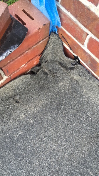 Bitumen roof sealing on brick wall with crack and sealing defect