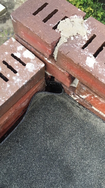 Close-up of brickwork with mortar residues and roof sealing material