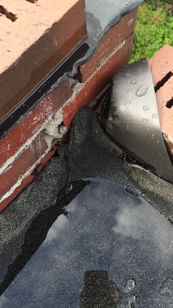 Close-up of roof edge with crumbly masonry, sealing layer, and water droplets