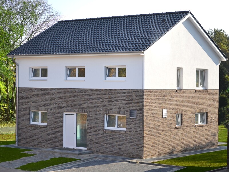 Two-storey house with brown brick base, white upper floor, dark tiled roof and garden.