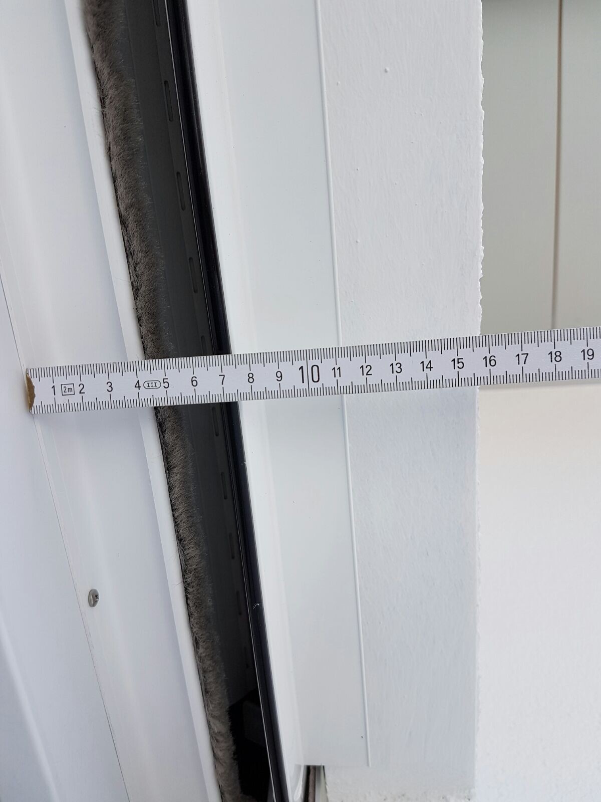 White door frame with measuring tape measuring the gap