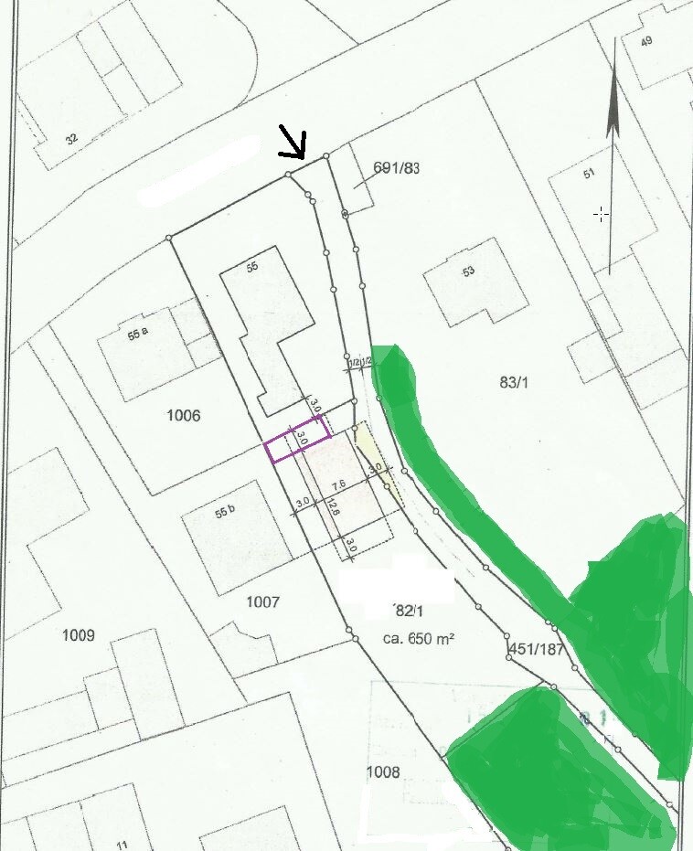 Site plan of a building plot with property boundaries, buildings, and arrow marker