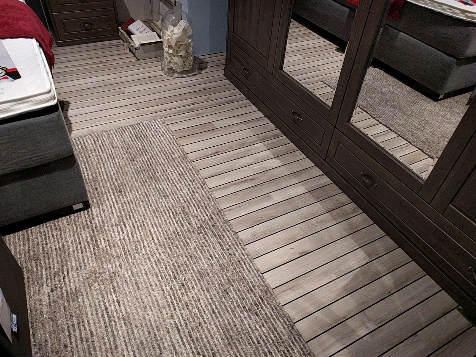 Bedroom with dark mirrored wardrobe, wooden floor, and carpet.