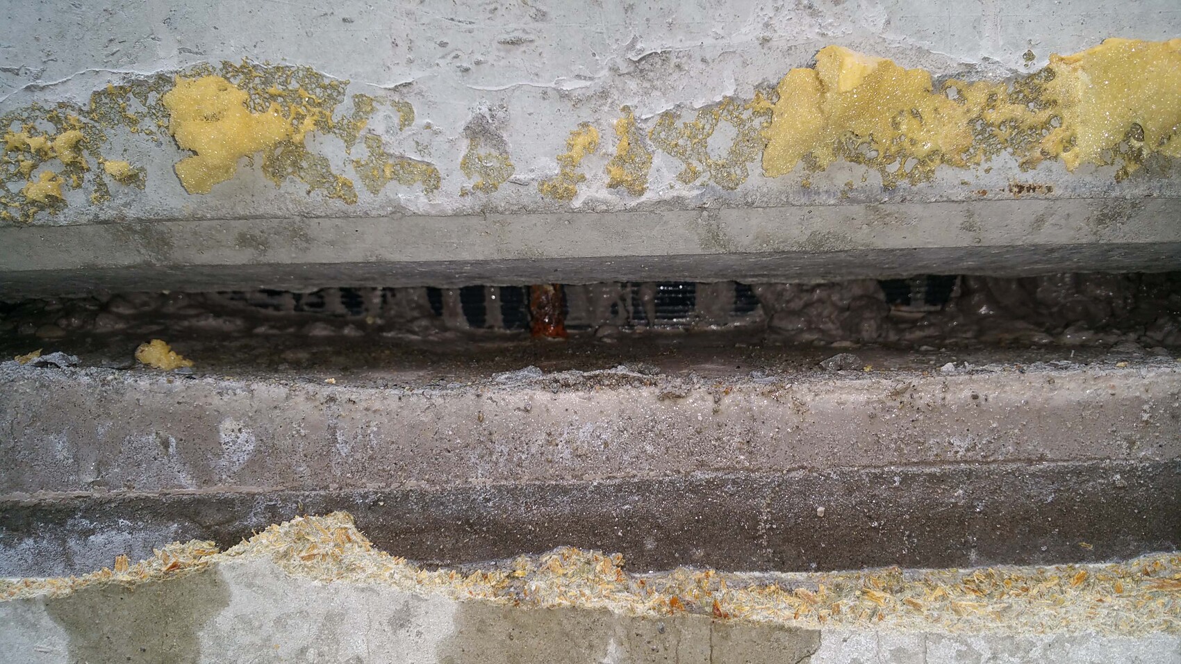 Basement wall with flaking plaster and visible yellow insulation