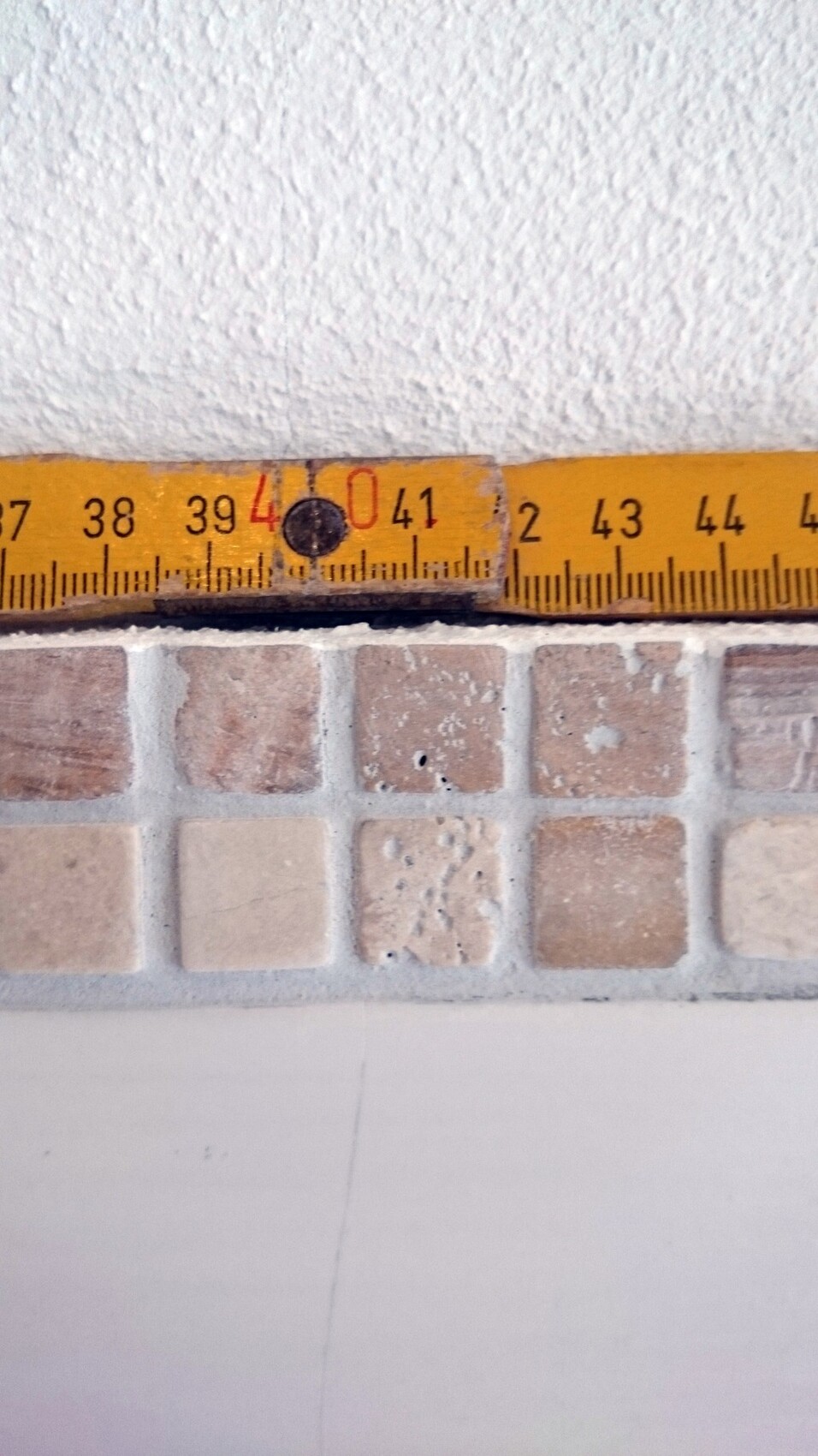 Tape measure lying over beige floor tiles against a bathroom wall