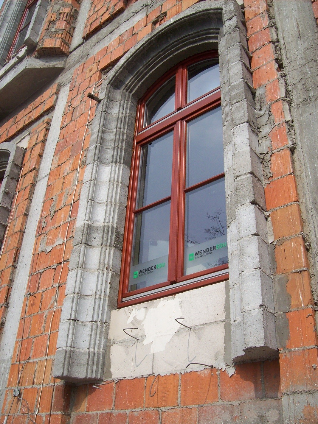Red window frame in raw brick construction under construction works