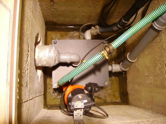 Basement room with building services pump, pipes and flexible hoses