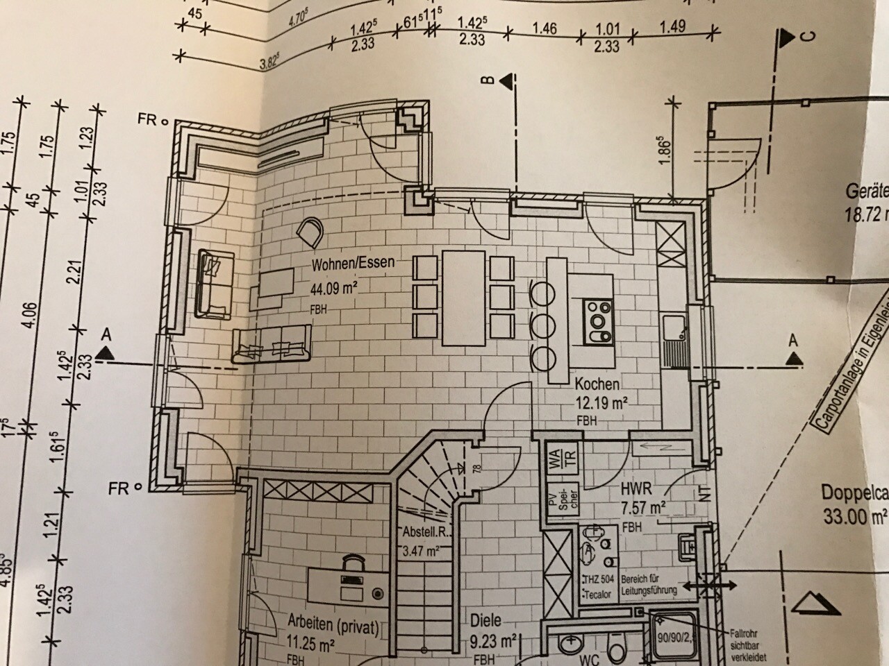 Offener Grundriss eines Wohn- und Küchenbereichs mit Essplatz, Treppe und Eingangsbereich.