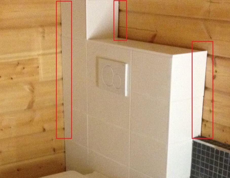 White wall-mounted toilet cistern installation behind tiles in a bathroom with wooden wall