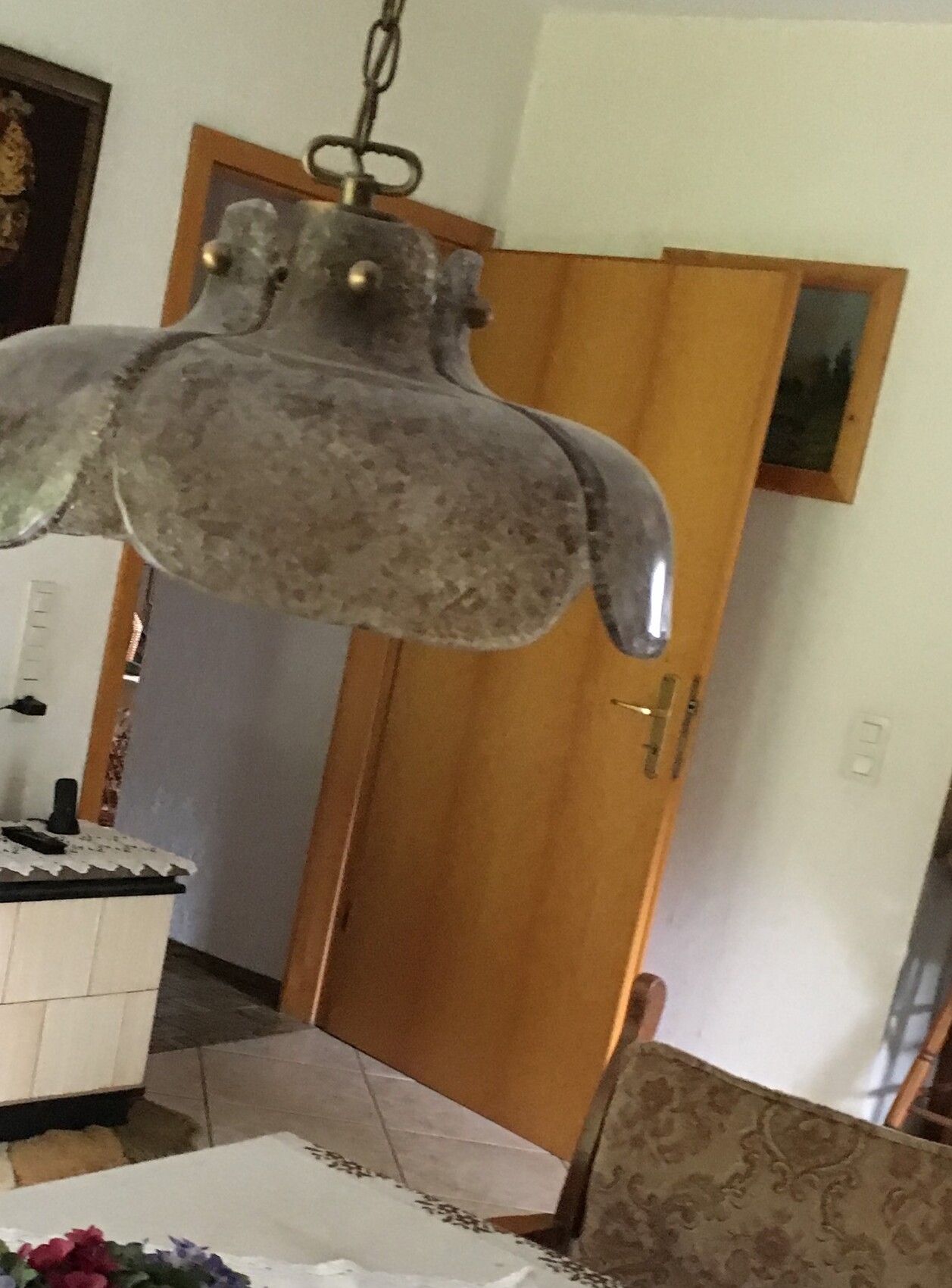 Large rusty metal pendant lamp over dining table in rustic dining area, background.
