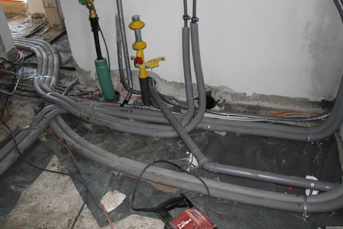 Basement construction site with pipes, valves, and cables for building services installation