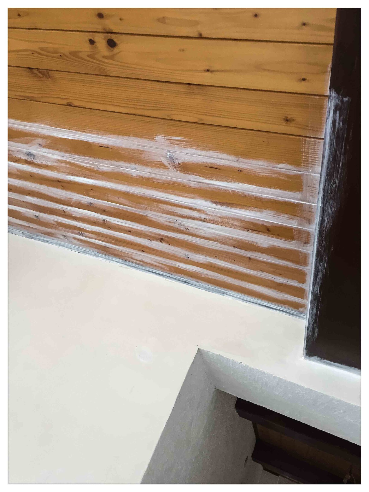 Interior wall made of wooden panels with white base area and visible joints