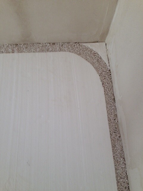 Corner of a bright bathroom floor with gravel edge