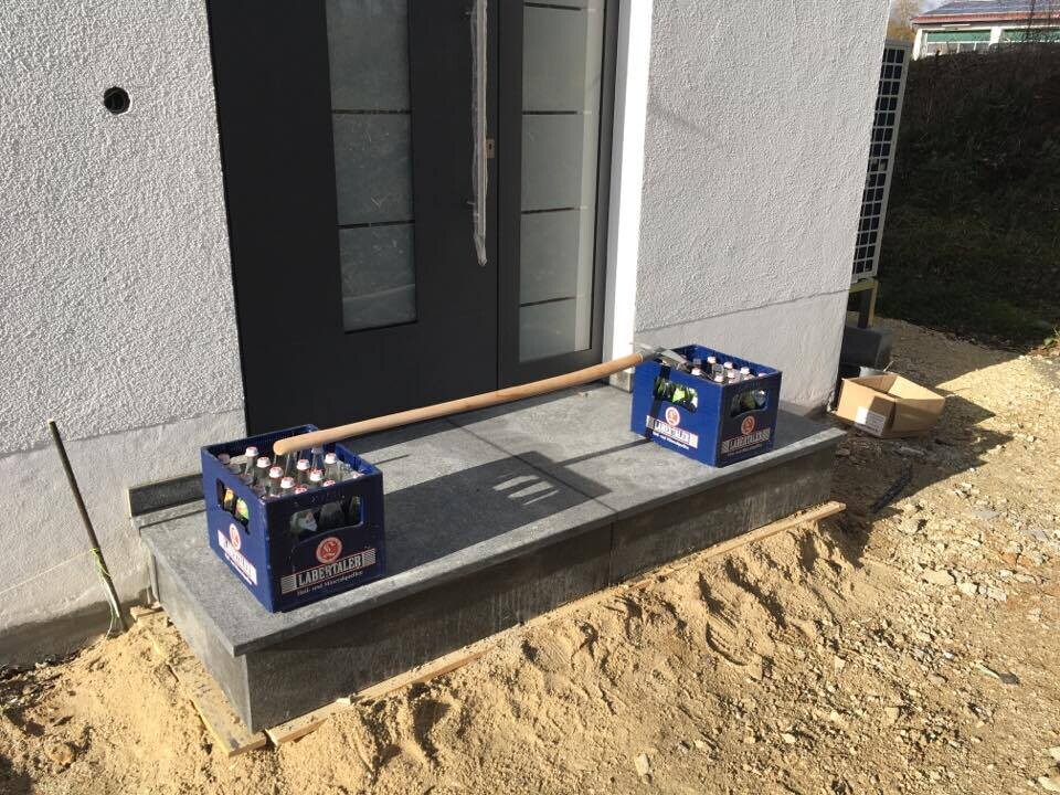 Exterior area of a new build house with entrance door, steps, and beer crates on the step.