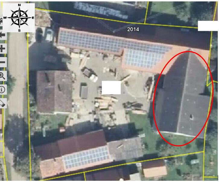 Aerial view of a plot with buildings; yellow boundary lines mark the site.