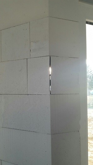 Innenraum-Eckbereich aus weißen Großformat-Betonblöcken; Spalt lässt Licht durch.