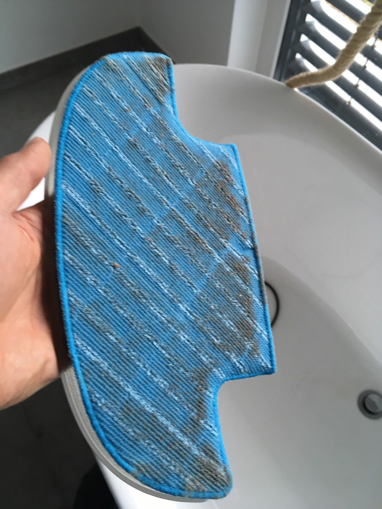 Blue microfiber cleaning pad with dirt on the edge of the sink