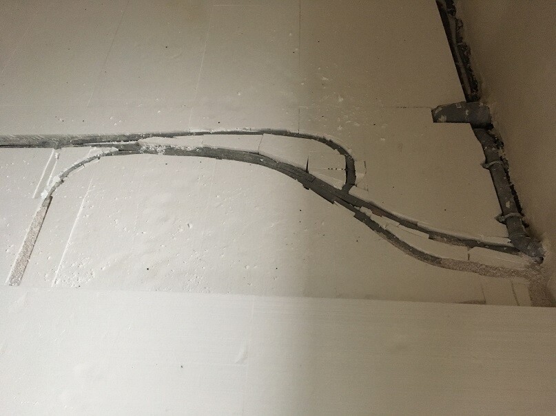 Rough floor construction with visible cables and pipes at the construction site