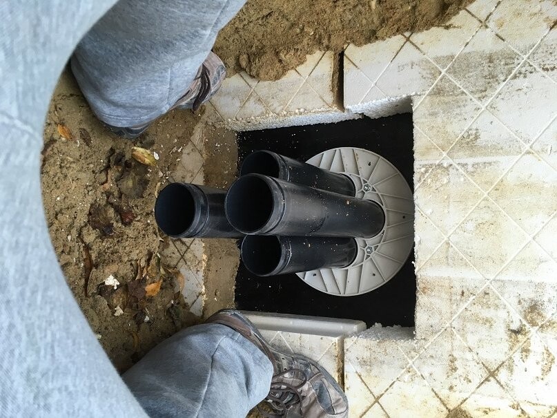 Sanitary installation in floor area with visible pipes and pipe casing
