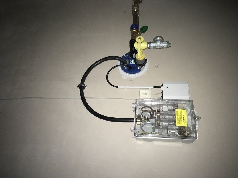 Building services installation components: gas valve, hoses, and electronics on the slab.