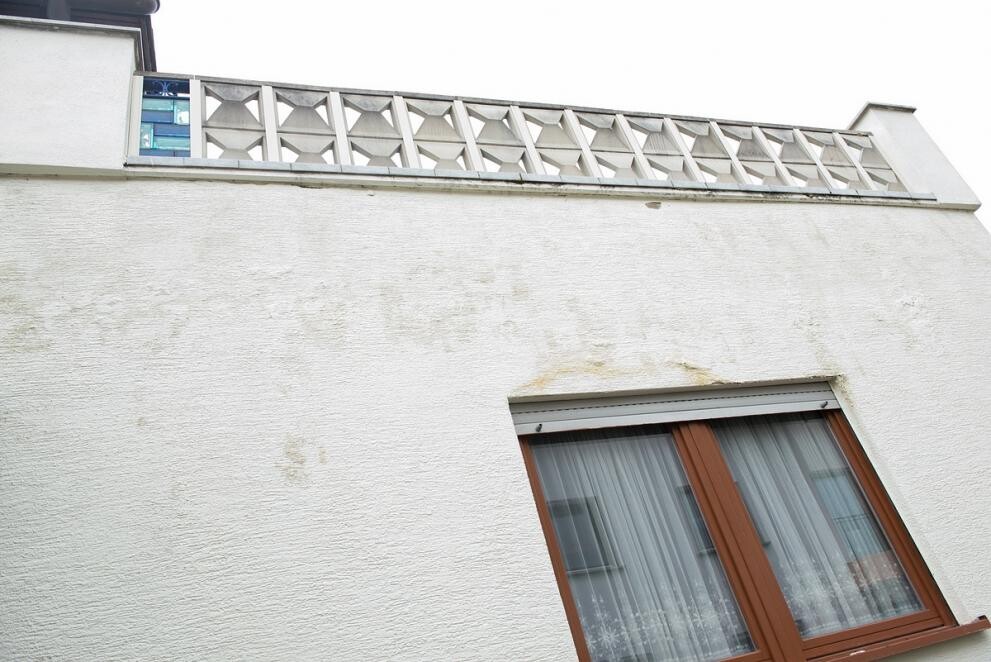 White facade with brown window frame and railing at the upper facade section