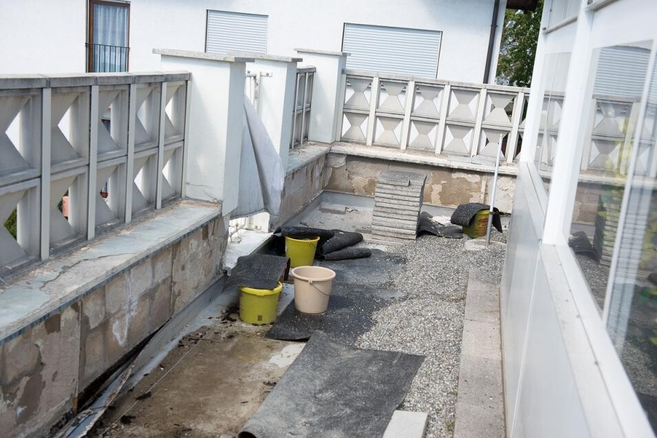 Roof terrace with building materials, buckets, and construction covers on a construction site