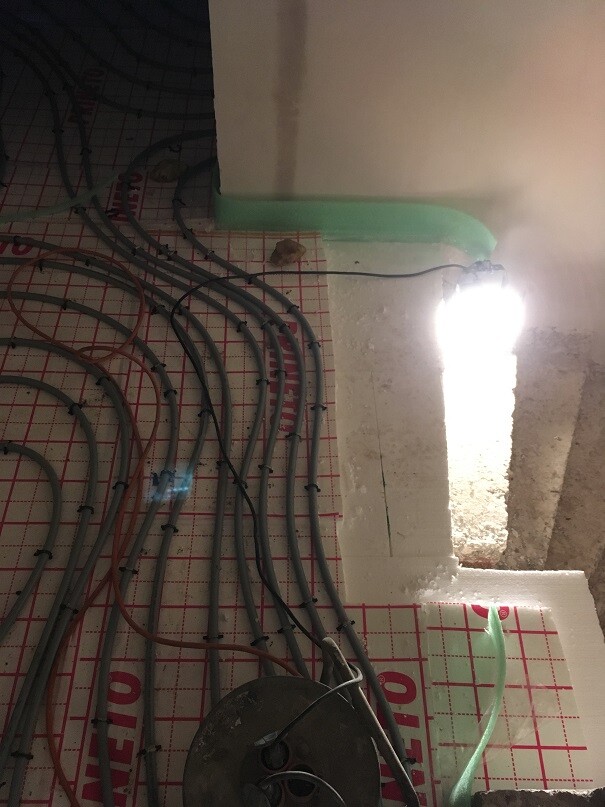 Construction site: many cables lying tangled on red grid flooring, green marked edge, lighting.