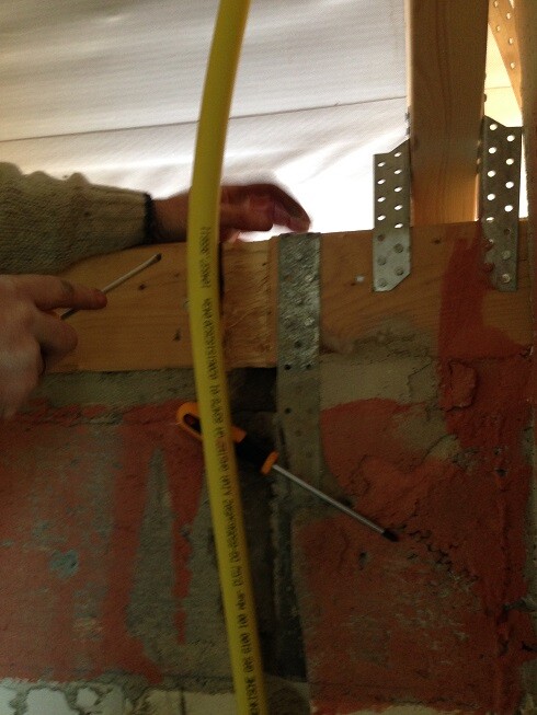 Shell construction wall frame with wooden and metal supports, metal brackets, and tape measure in the wall.