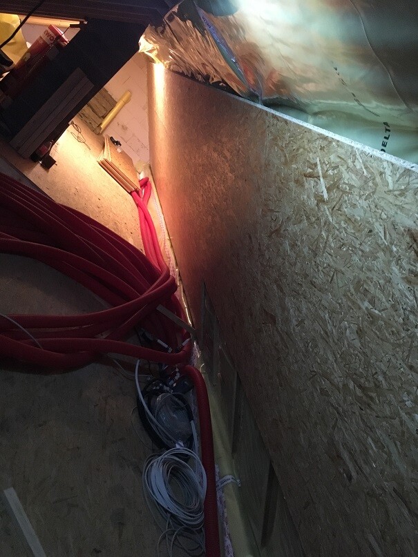 Blick in Bauinstallation mit roten Elektroleitungen, Kabelrollen und OSB-Wandplatten.