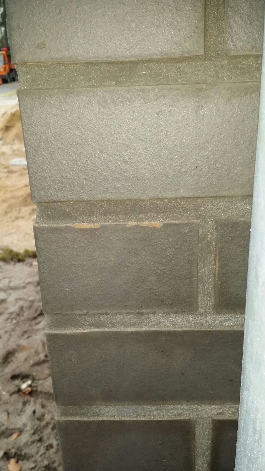 Close-up of an exterior wall made of concrete blocks during shell construction, construction site in the background