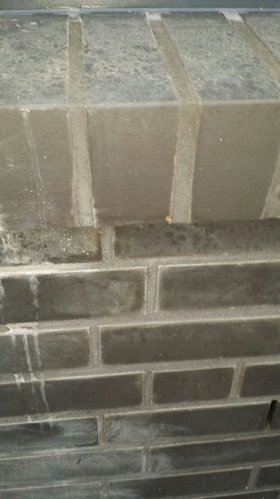 Gray concrete block wall in shell construction, roughly laid with visible joints.
