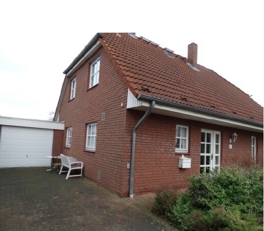 Exterior view of a red brick house with garage and pitched roof