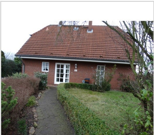 Front view of a red brick house with garden path and hedges.