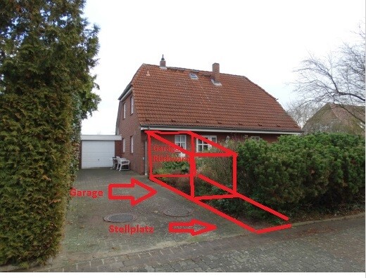 Front view of a detached house with garage, driveway, and hedge