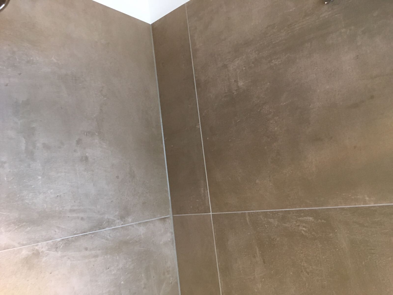 Corner of two brown tiled walls with visible grout lines and edge line.