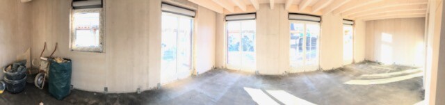 Unprocessed interior of a shell construction with concrete walls, windows, and untreated floor
