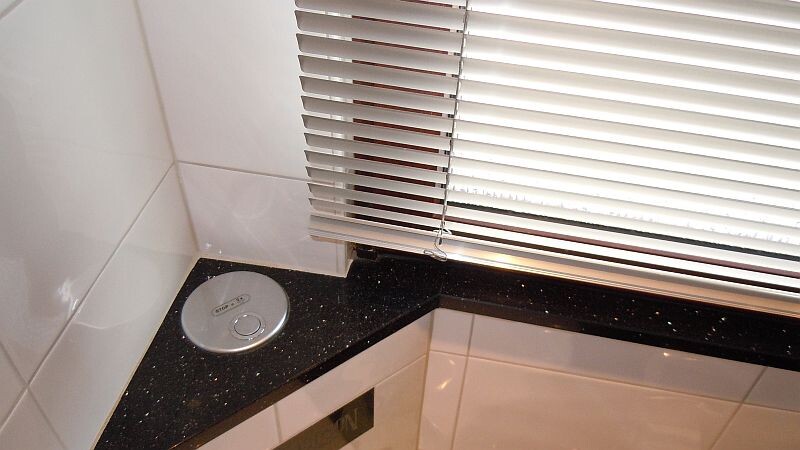 Kitchen area with black granite countertop, white tiles, and window blinds