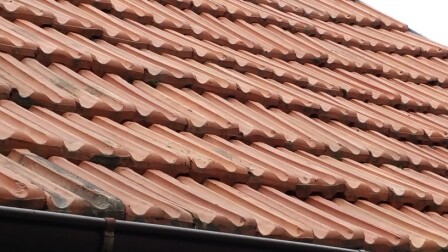 Close-up of red roof tiles with wavy profiles on a roof surface