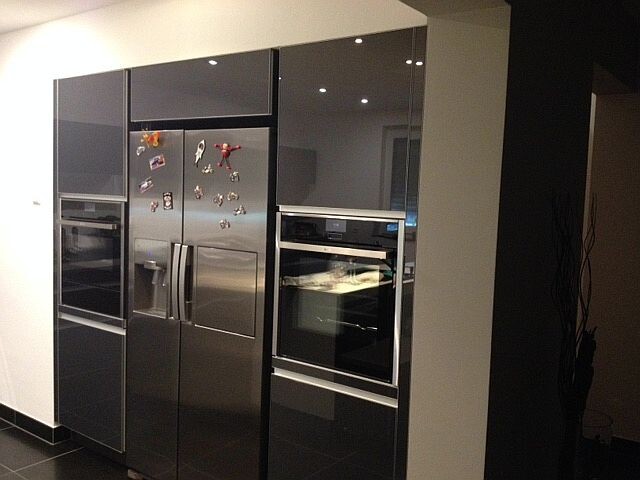 Modern stainless steel kitchen with refrigerator and built-in ovens in a dark kitchen unit
