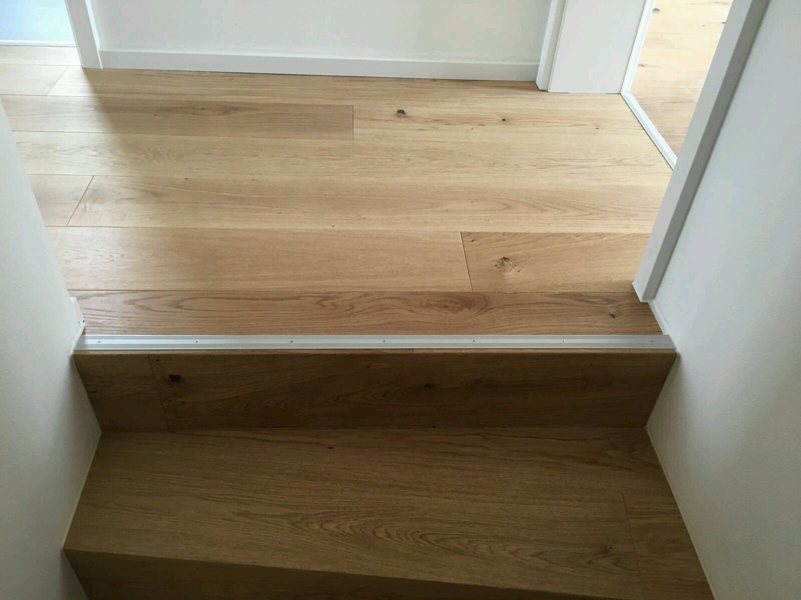 Interior view: Wooden floor with steps and metal transition between two levels.