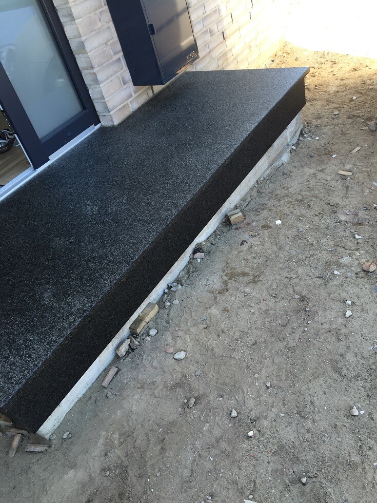 Black granite bench as an outdoor bench in front of the house facade at the entrance