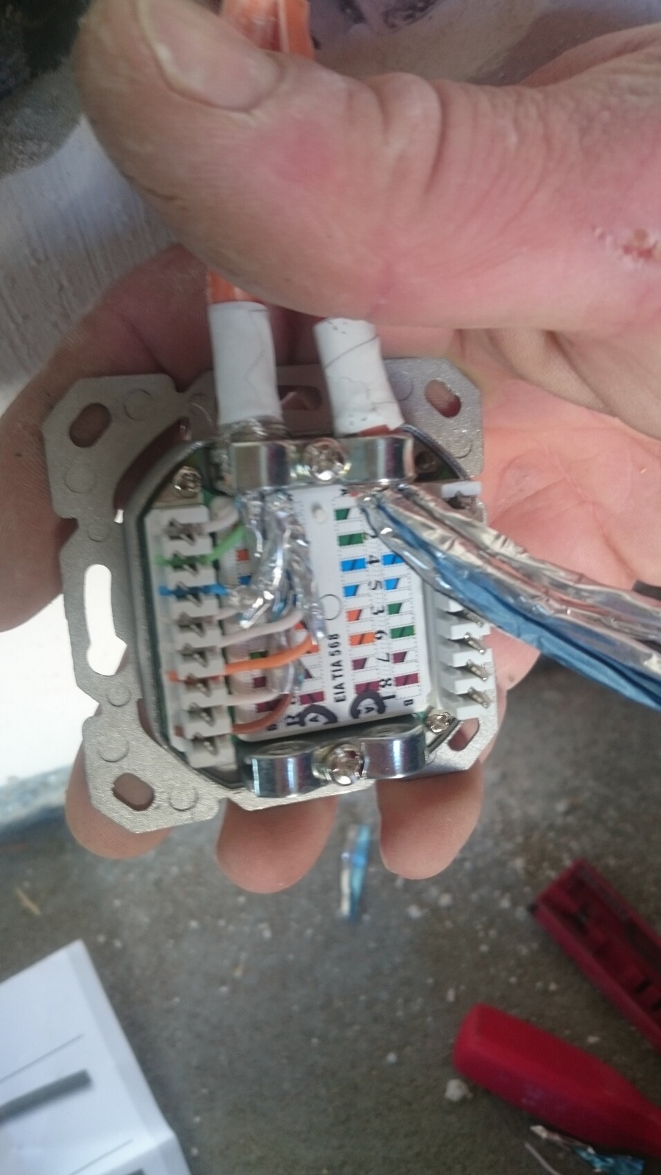 Open electrical wiring in a metal back box with colored conductors and terminal strip.