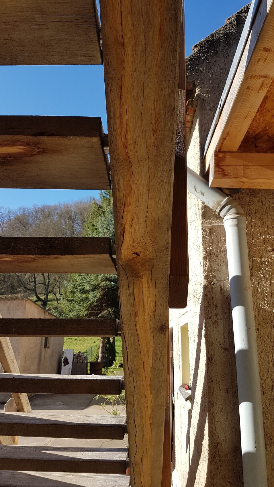 Außenbereich mit Holzbalken, Rohbaukonstruktion und Regenrinne sichtbar.