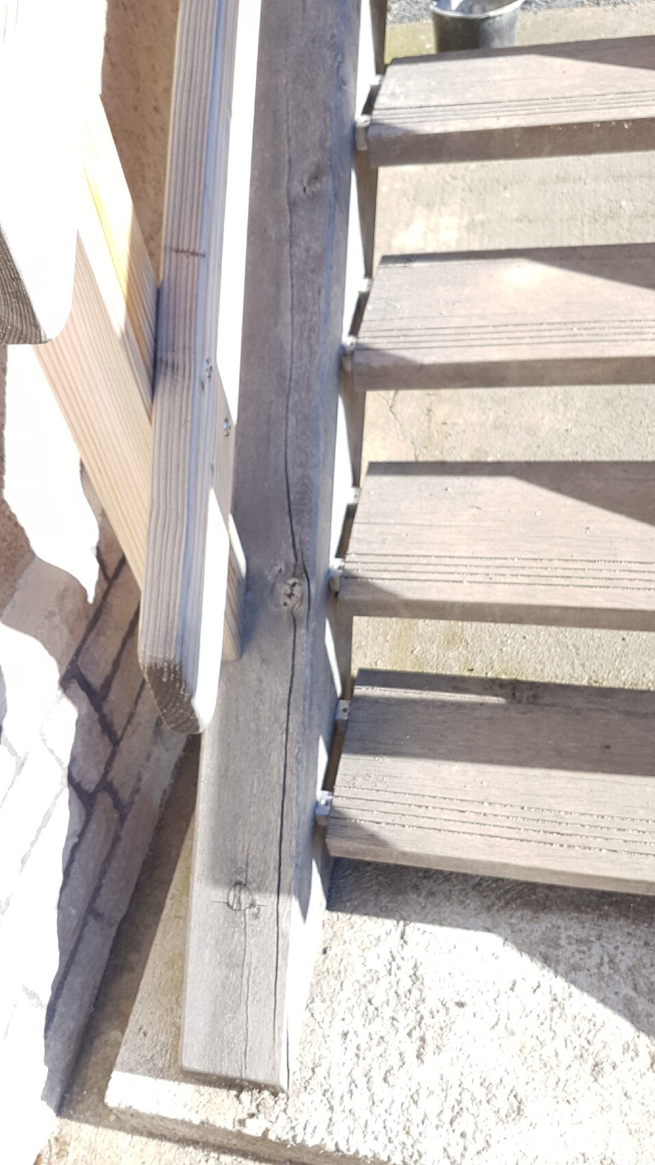 Außen-Holztreppe mit Geländer an Mauer und Betonboden
