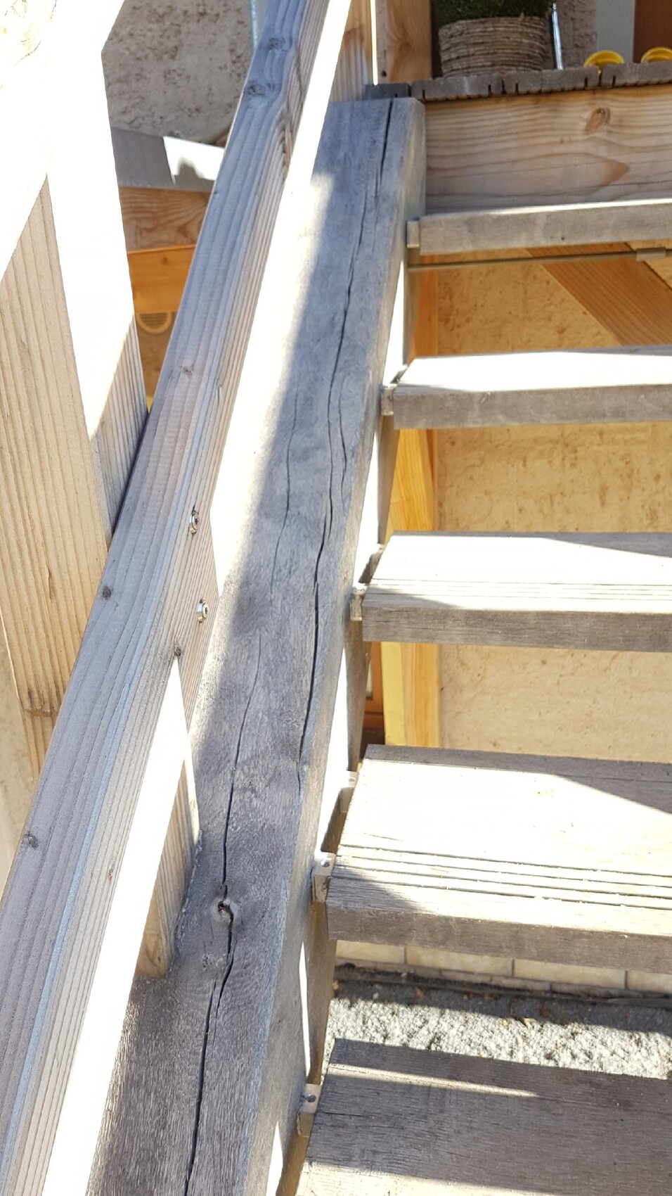 Außen-Holztreppe mit rissigem Geländerpfosten und Stufen auf Baustelle