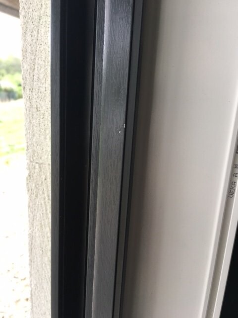 Close-up of a dark metal window frame next to a light-colored wall