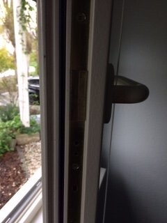 Close-up of a door handle and door frame with a view outside to the garden.