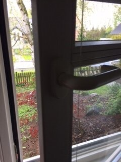 Door handle on glass door with a view outside to the garden